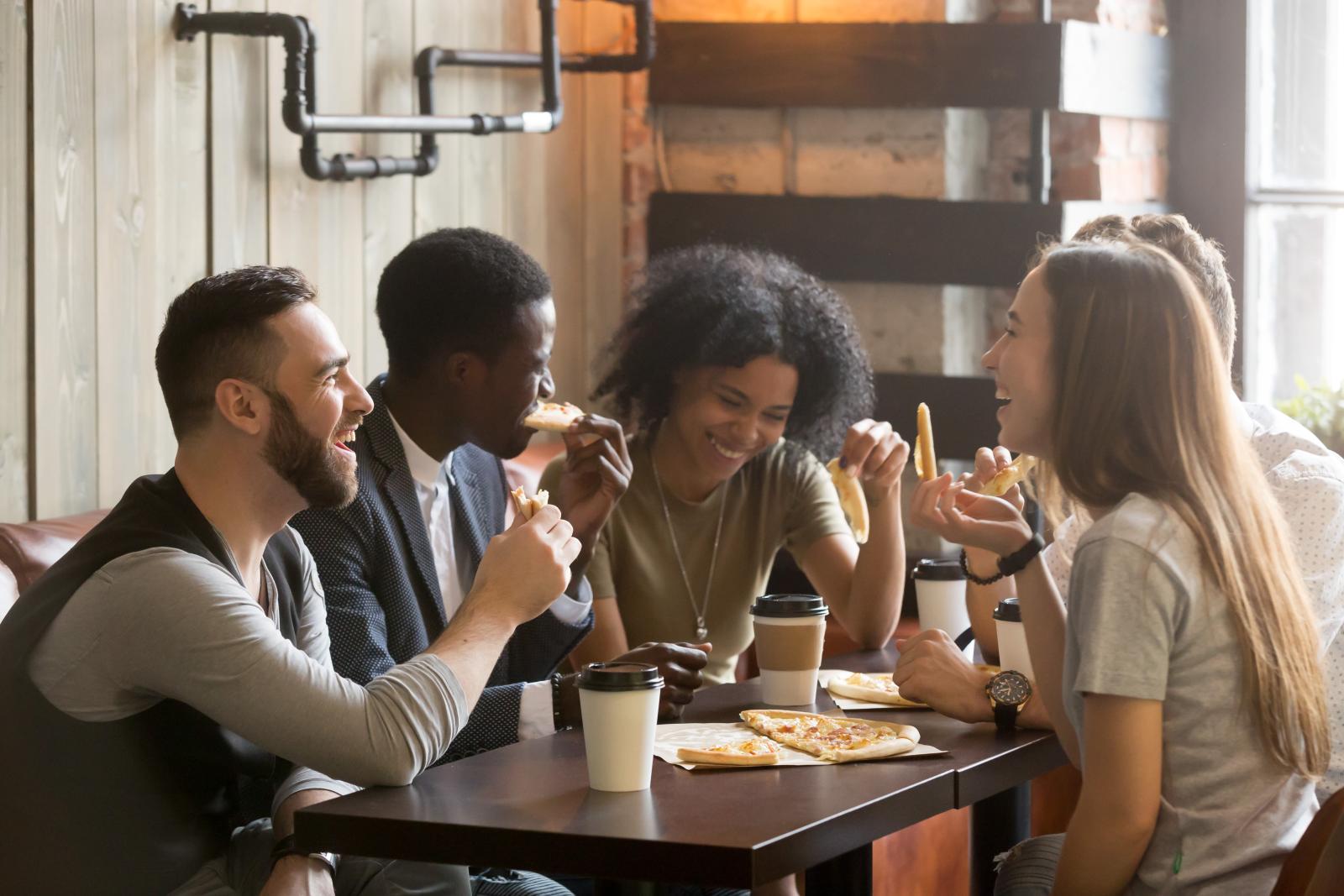 A group of friends enjoying food and coffee together in a cozy indoor setting with warm, rustic decor.